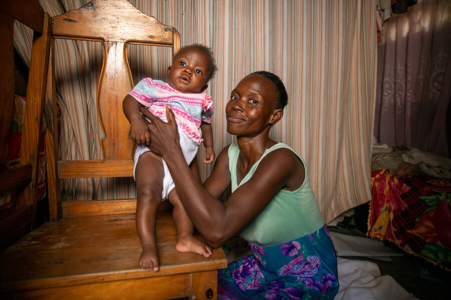 A woman holds her baby in her home in Haiti
