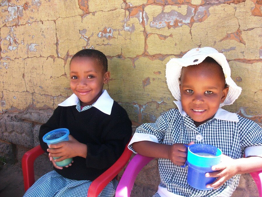 Kamohelo and Thato enjoy their breakfast porridge at Thuto Ke Leseli Primary School, Lesotho. Photo: Lesotho CO