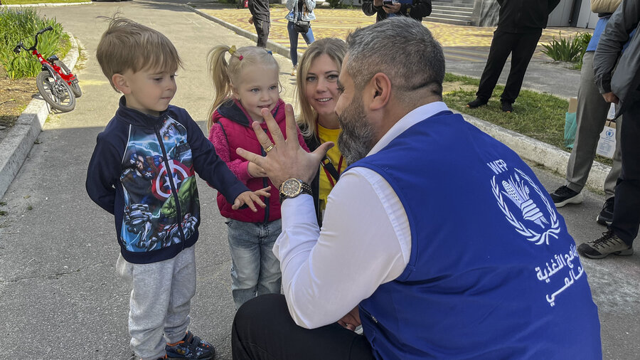 Man kneeling and speaking with children