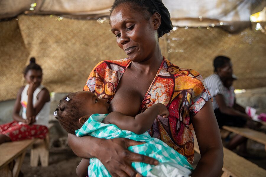 A mother breastfeeds her daughter in a small house