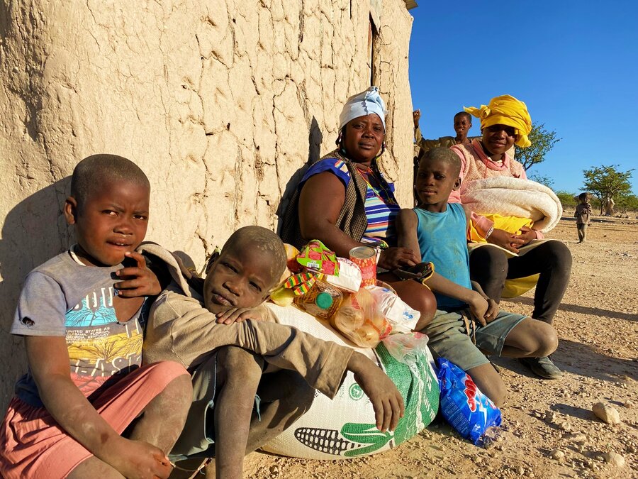 Kasesa and her children sit outside their home with their food purchases. Photo: WFP/Luise Shikongo