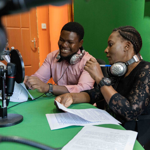 a man and a woman are talking to a mic