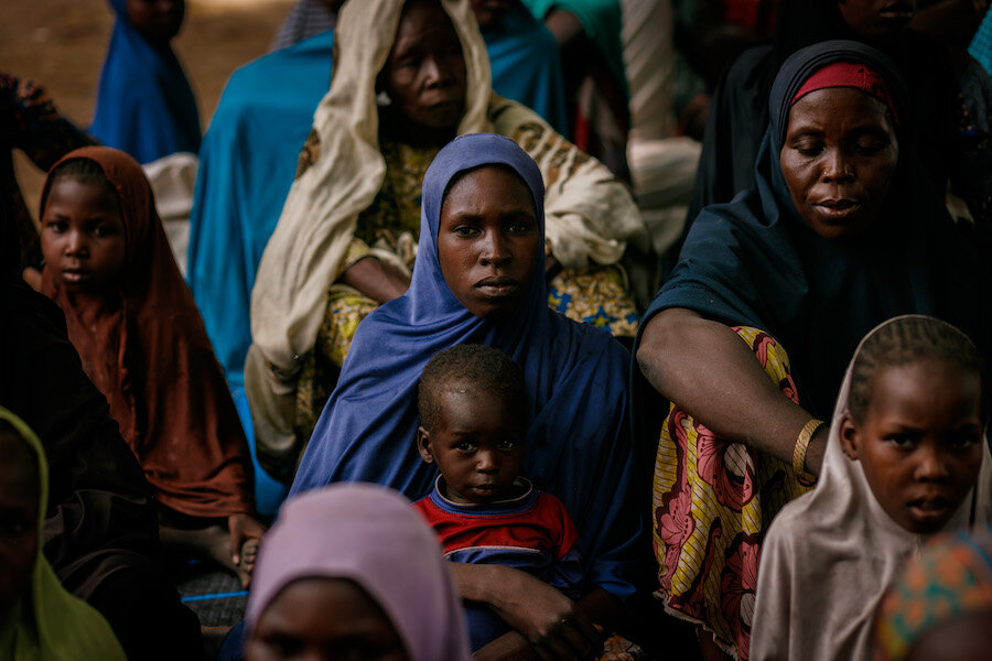 Group of beneficiaries sat on floor looking towards camera