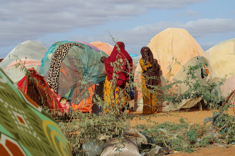 People standing outside a tent in a refugee camp