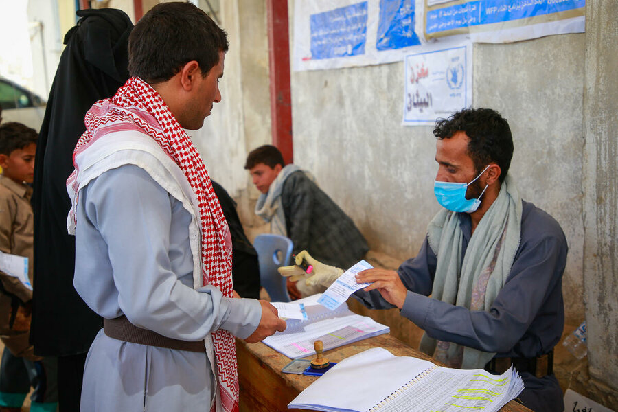 Sadeq (L) gets his papers checked to receive WFP vouchers he can trade in for food. Photo: WFP/Rabie Al-Zuhairi