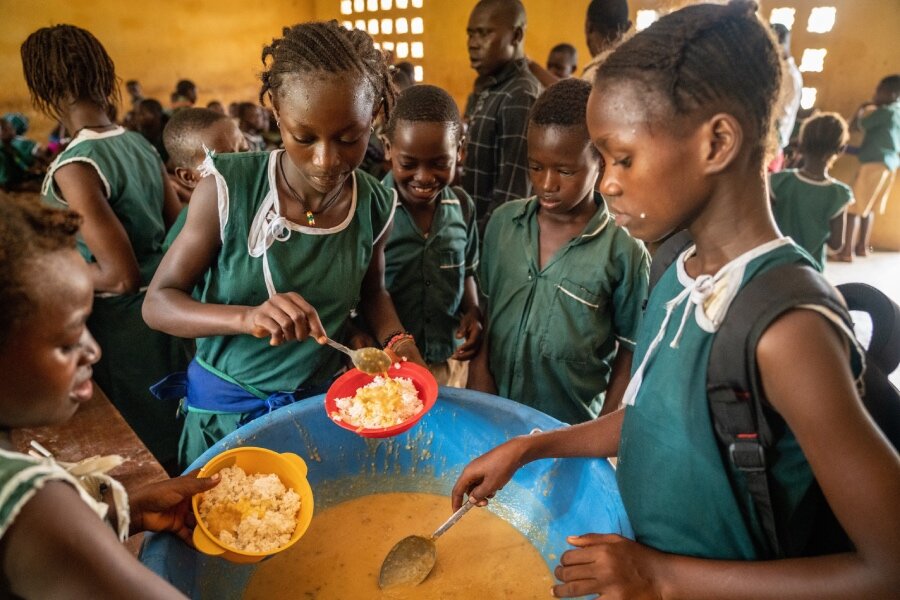 One of fatmata's daughters (C) tucks into a WFP school meal. Photo: WFP/Michael Duff