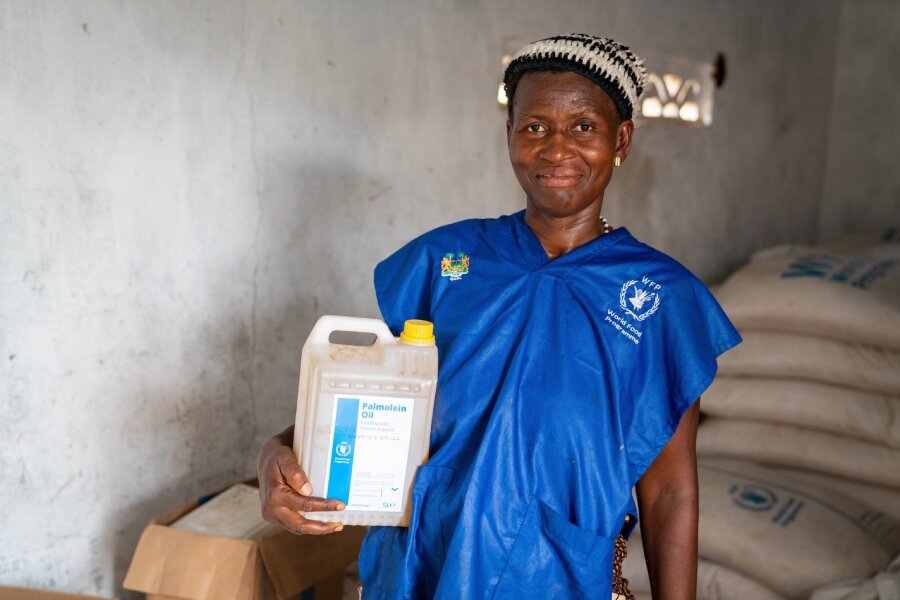 Fatmata picks up WFP vegetable oil she'll be using to cook the school meal. Photo: WFP/Michael Duff