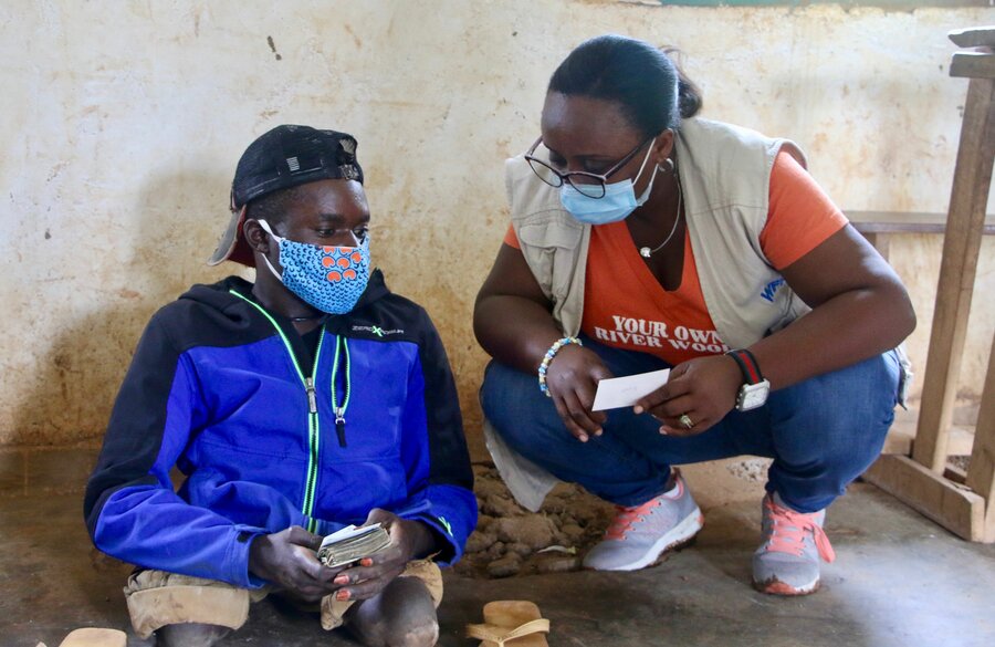 Sadi chats with a WFP staff member after receiving his cash assistance. Photo: WFP/Benjamin Anguandia