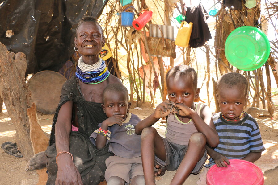 Alice posing with her three grandchildren 