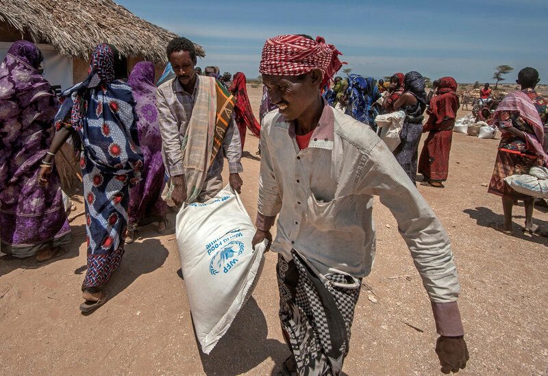 People carrying bags of food at a WFP distribution site