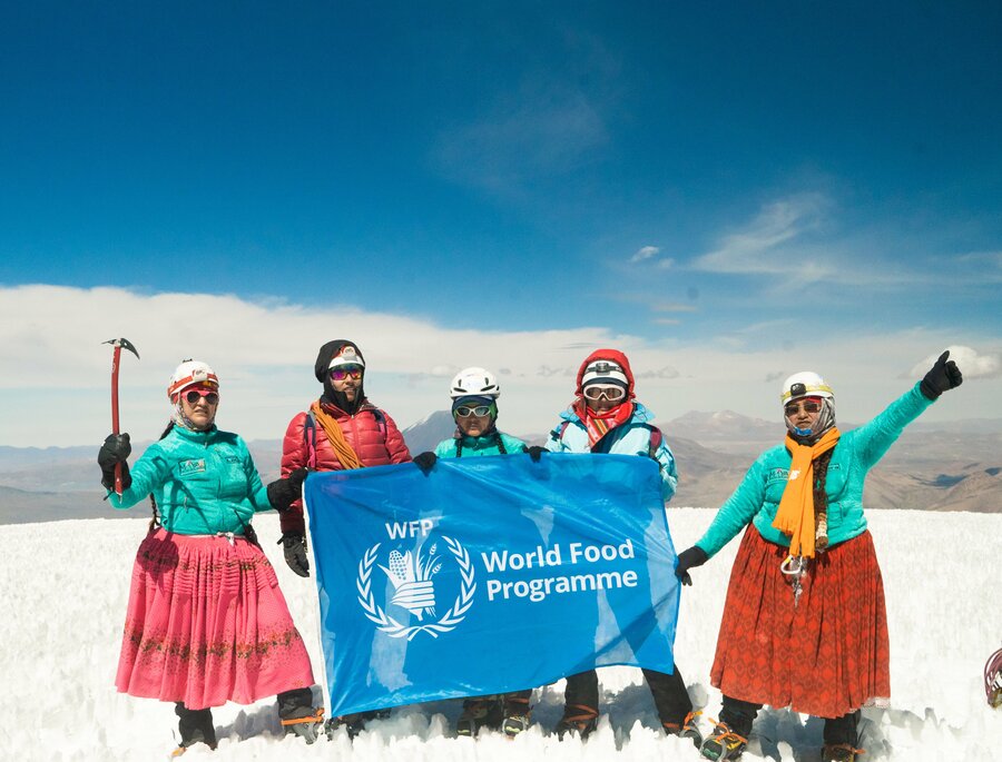 The Cholitas Escaladoras atop a mountain with a WFP flag