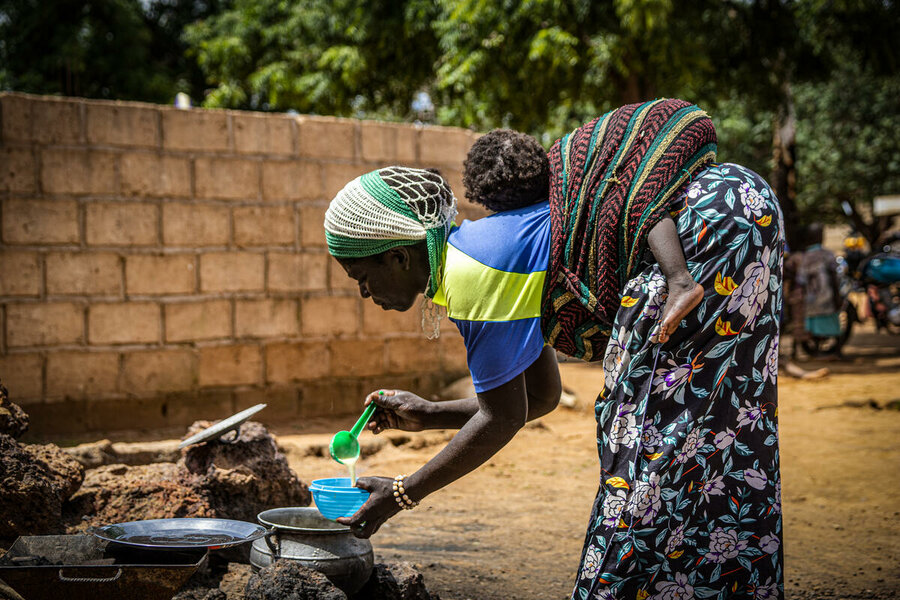 In Kaya, Burkina Faso, a mother carrying her 10-month-old child pours fortified porridge into a bowl, thanks to a WFP-supported project. Photo: WFP/Cheick Omar Bandaogo