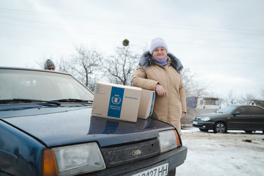 A woman beneficiary standing next to the WFP food packages in Ukraine
