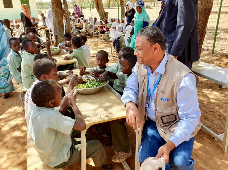 WFP's Hameed Nuru with students in Darfur, Sudan, as they enjoyed a meal cooked with ingredients from their school garden. The visit took place when Nuru was WFP Sudan Country Director. Photo: WFP Sudan  