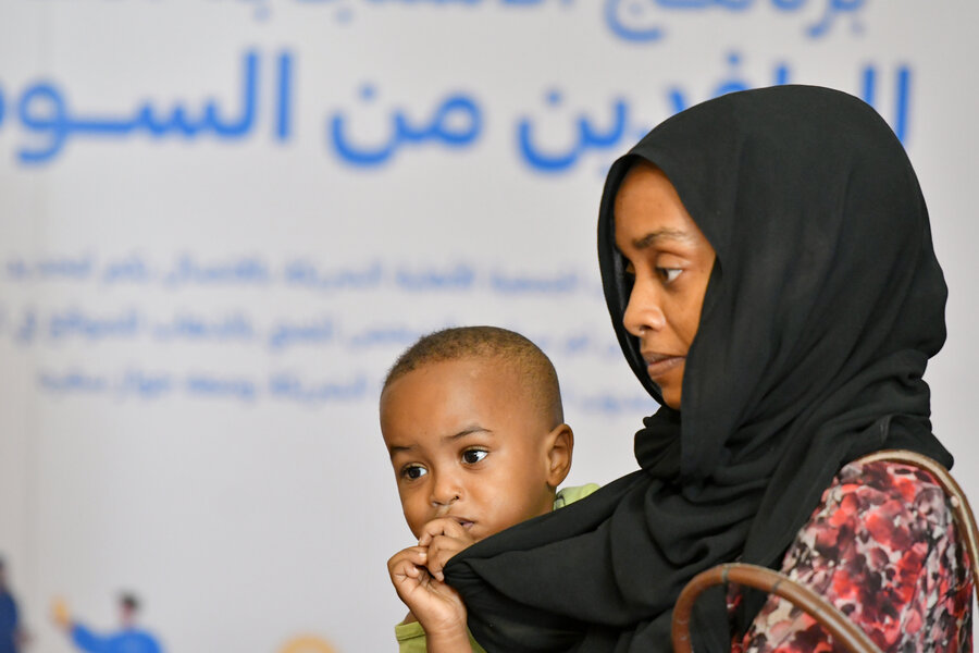 A Sudanese woman awaits cash assistance across the border in Egypt