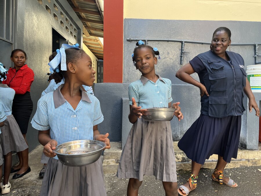 WFP staffer with two schoolgirls in uniform at a school supported by WFP near Jeremie