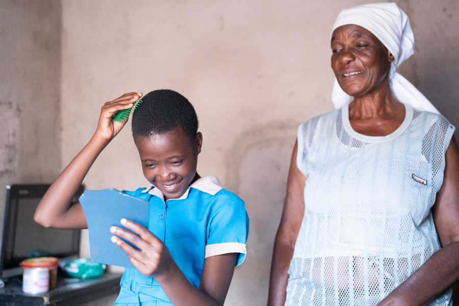 Egnetter, 64, watches her granddaughter comb her hair at home in Bulayo, Zimbabwe