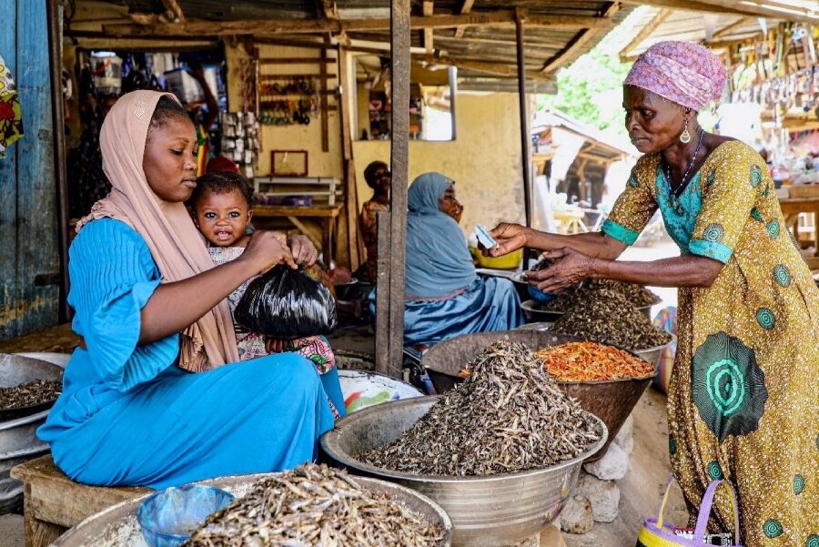 Youlka (R) buys food for dinner at a market in Togo's Savanes region, where many displaced people are seeking shelter from violence. Photo: WFP/Richard Mbouet.jpg