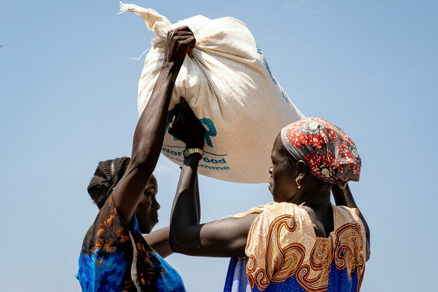 Two women lift bag in south sudan