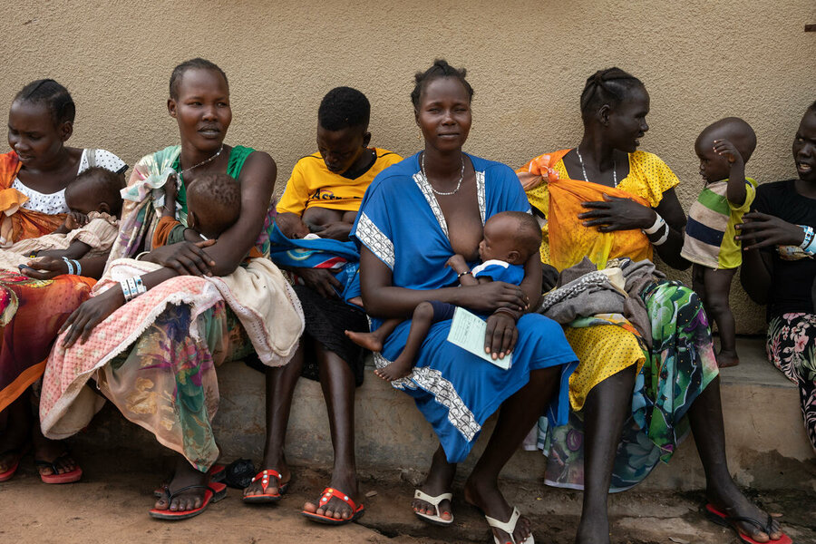 A group of mothers seating next to each other, breastfeed their babies