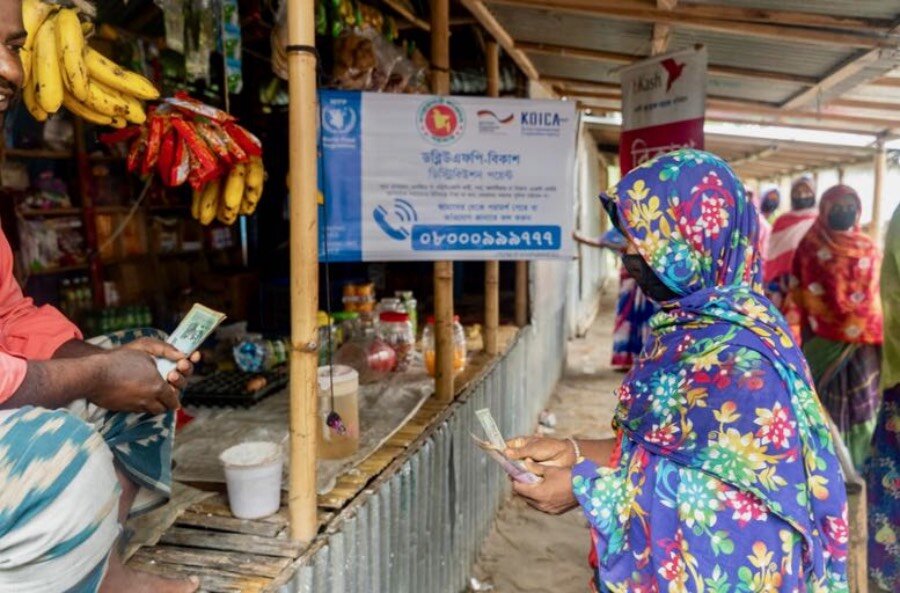 A woman buys food with WFP cash assistance she received during recent Bangladesh floods. Photo: WFP/Mehedi Rahman
