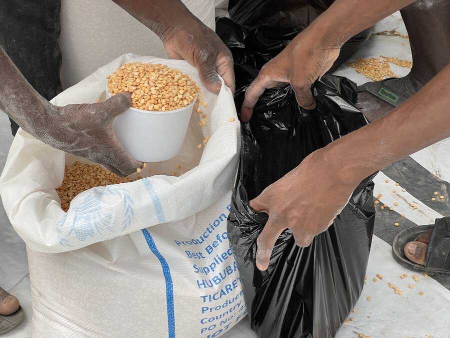 A person transfers food from a WFP bag to a small black bag
