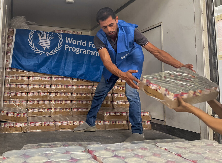 Man unloading tins of food from a truck