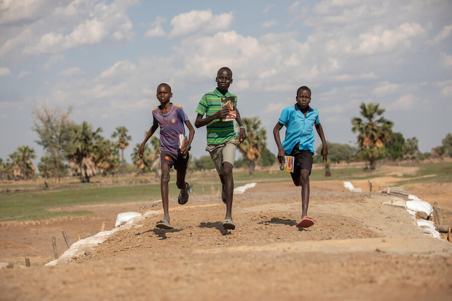 Boys run over a dyke, built with the support of WFP and its partners, that also serves as a road in Alek, in South Sudan's  Warrap State, allowing people access to critical services during floods. Photo: WFP/Samantha Reinders