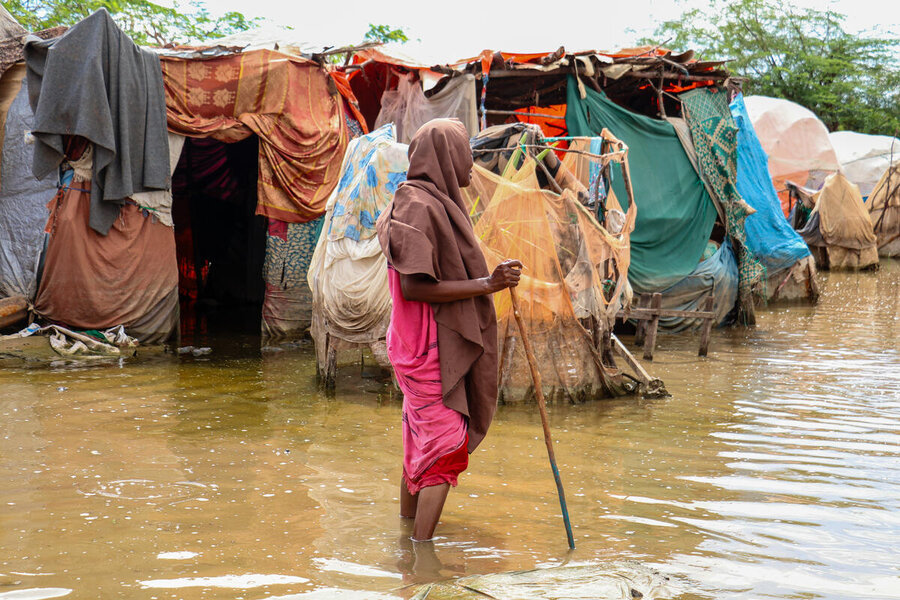 A woman walks ankle-deep in flood waters in a camp for displaced people in Somalia
