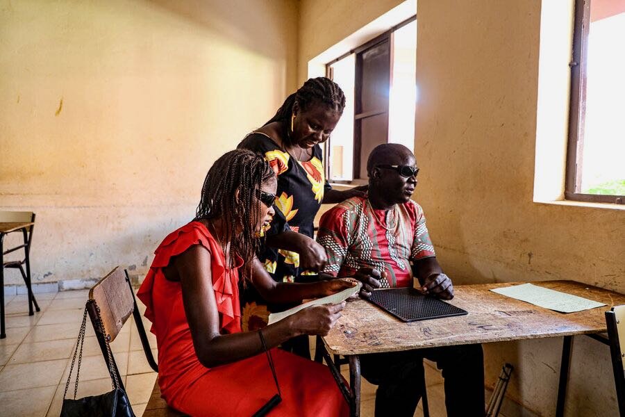 A school monitor (L) and a teacher (C) supervise a visually impaired adult at Bengala Brenca school in Bissau. Photo: WFP/Richard Mbouet