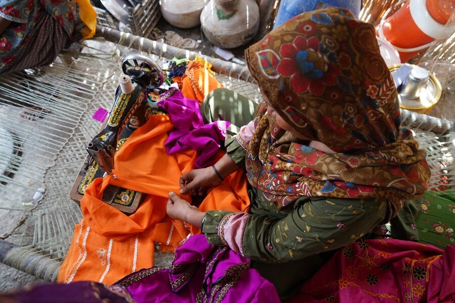 Husan Bano's stitches a bright orange dress for her neighbour's wedding.  WFP/Anam Abbas