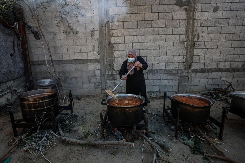 Palestine. Woman uses firewood to cook WFP hot meals in UN shelter