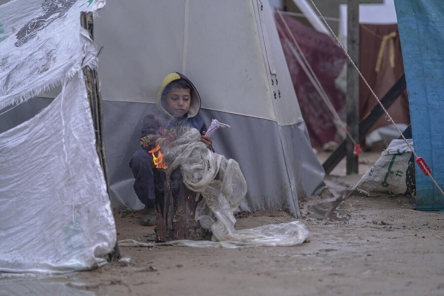 Boy tries to keep warm in camp in Gaza Photo Jaber Badwan