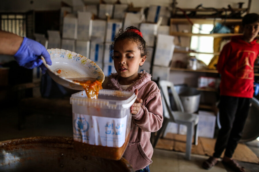 A little girl receives WFP food in Deir Albalah, in central Gaza. Famine is imminent in parts of the enclave however, as humanitarian aid piles up on its borders due to access constraints. Photo: WFP/Ali Jadallah 