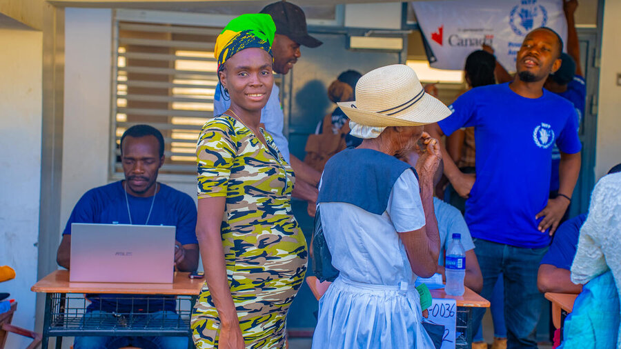a pregnant woman smiles to the camera as she queues for a WFP distribution in Haiti