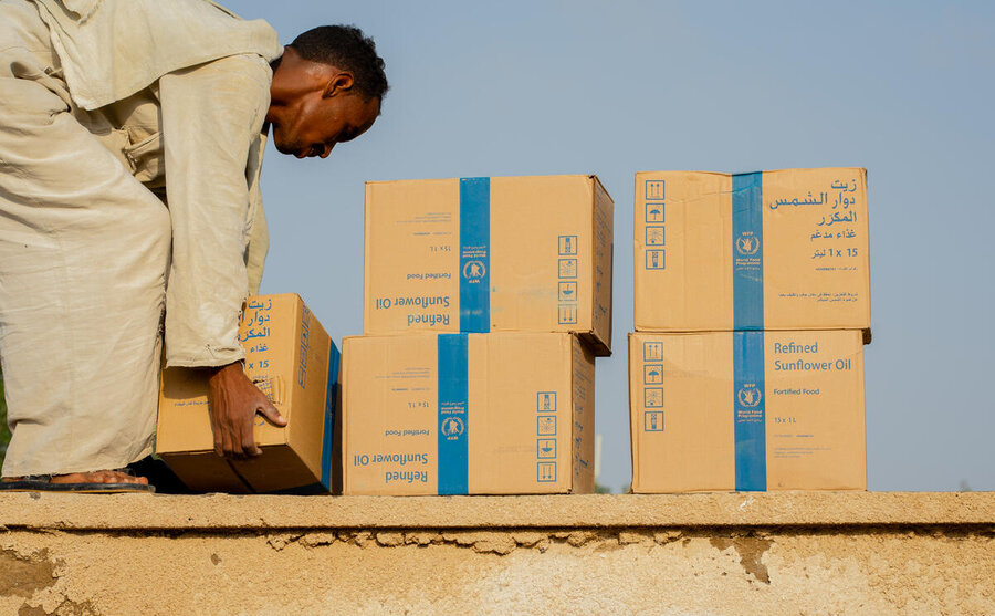 A Sudanese man stacks boxes of food assistance with WFP logo