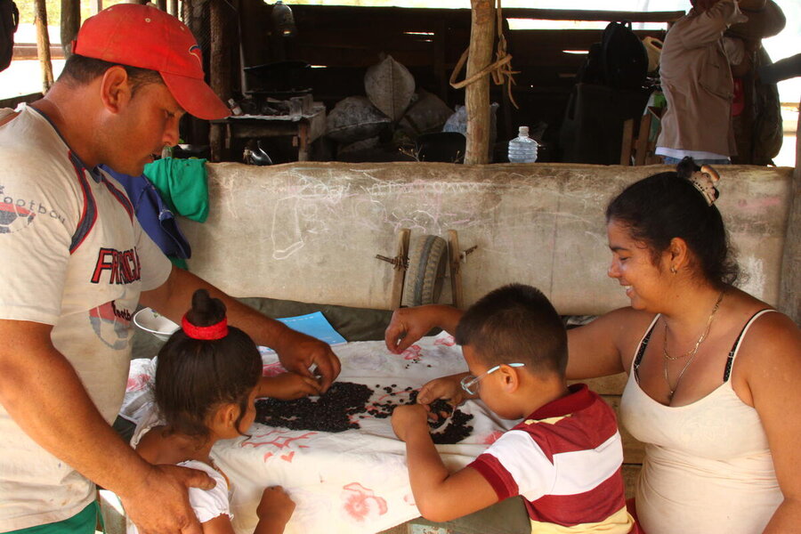 A Cuban family - mother, father, a young boy and girl - looks at black beans on a table