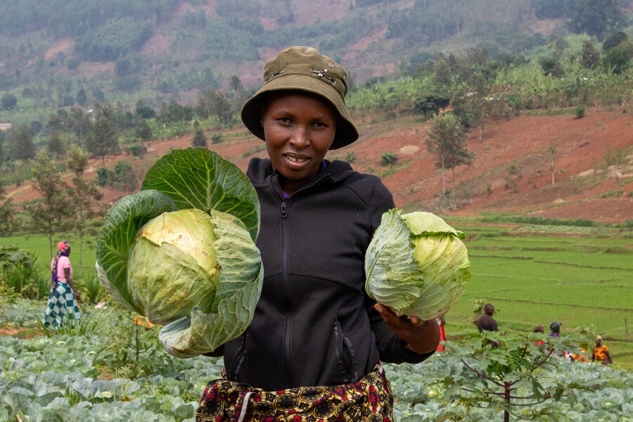 A woman with two big cabbages she's grown in Rwanda