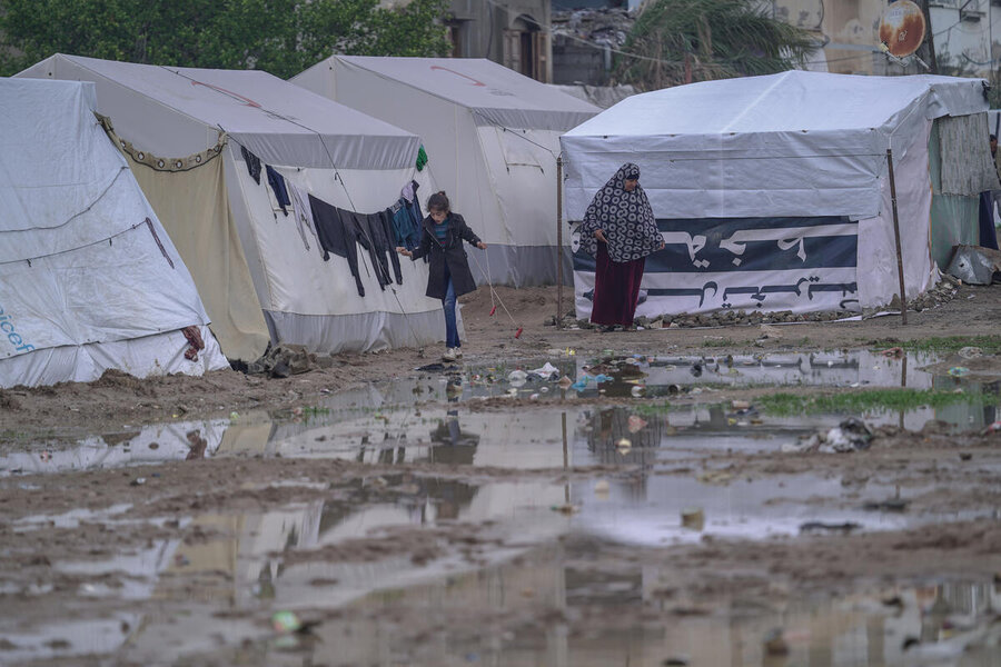 A woman and girl pick their way through the mud in a makeshift tent camp. Along with intense hunger, many Gazans have endured a winter of cold and bombs. Photo: WFP/Jaber Badwan