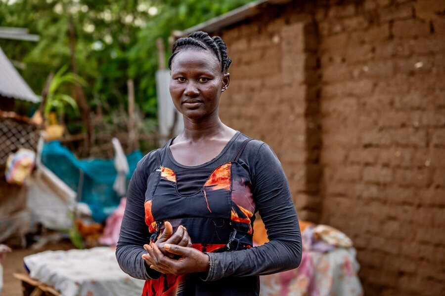 Refugee Waad (standing in front of a mud-brick house) helps to feed her family by selling eggs and some of the chickens she's raising at Kakuma camp. Photo: WFP/Dennis Matendechere
