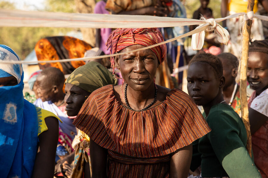 A woman in a crown waiting at a distribution in South Sudan looks into the camera