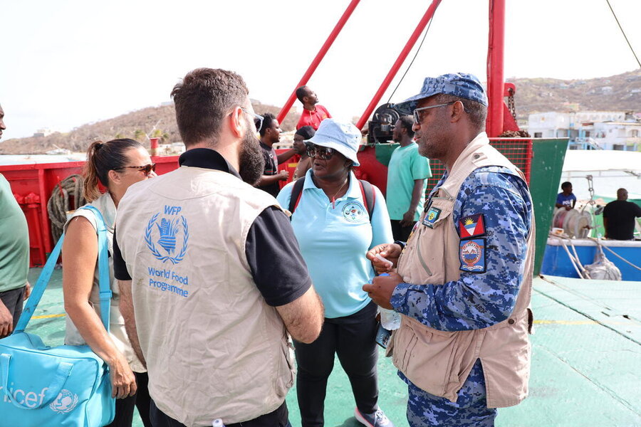 A WFP staffer at a harbour talks to humanitarian and government colleagues