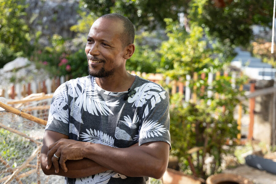 A man in a tropical patterned t shirt smiles crossing his arms