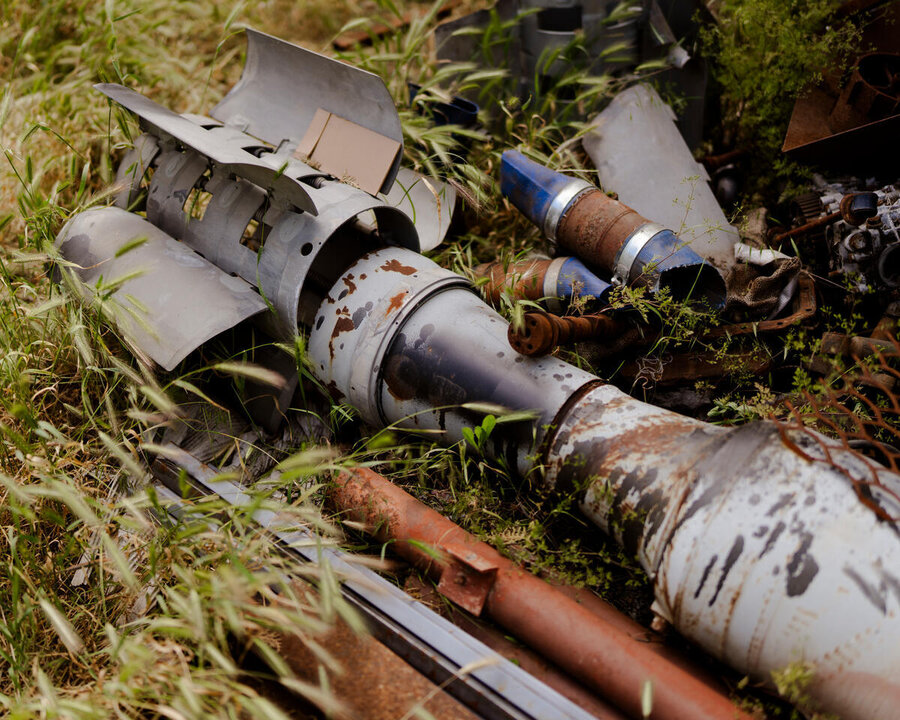 Close-up of unexploded small missile and parts on a bed of grass