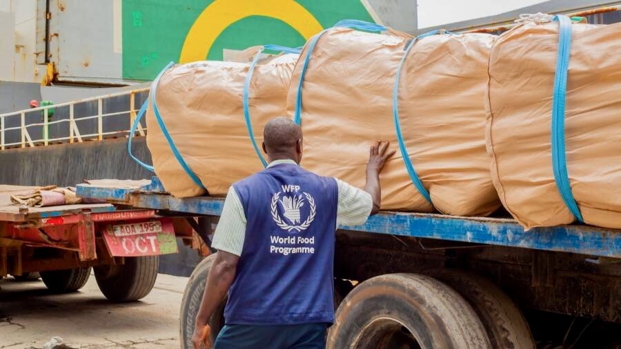 A WFP employee checks brown sacks of food loaded on to a truck at Sierra Leone's port. Photo: WFP/Inkee Media