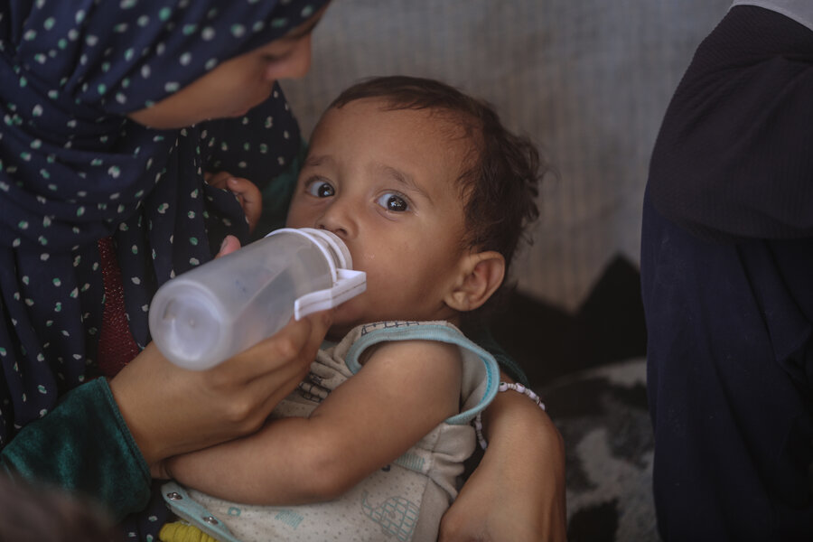 A woman gives a baby a bottle of water for lack of formula. Photo: WFP/Ali Jadallah