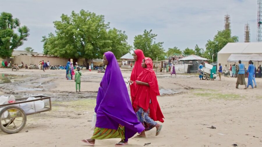 Women in colourful robes walk through a displacement camp in northeastern Nigeria. Photo: WFP/Arete