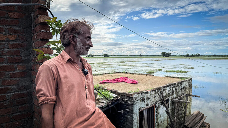 A bearded late middle age man looks across an expanse of flooded fields