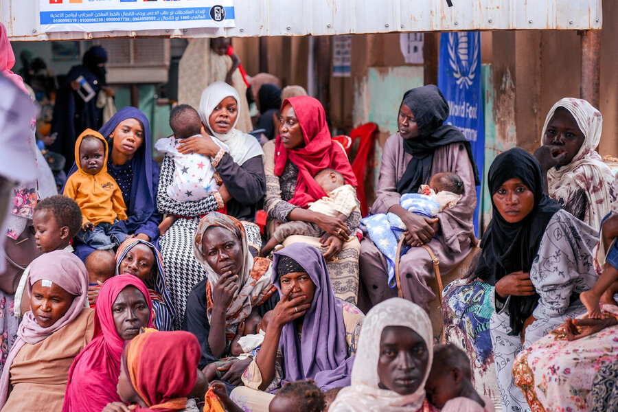 The faces of women in red, purple, brown Islamic outfits at a distribution centre in Sudan - a number of faces looking directly at the camera