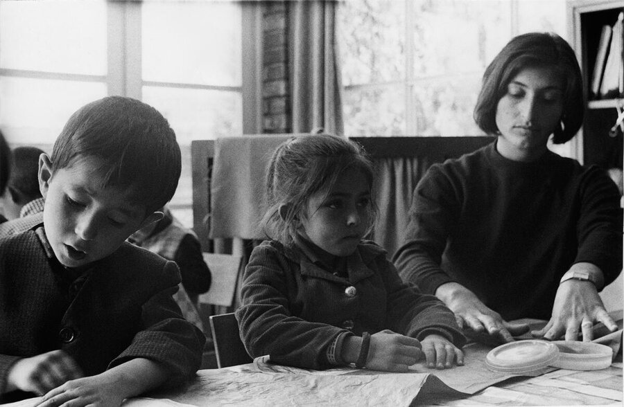 A black and white photo of a female teacher in Kabul with a girl and a boy in class in 1967
